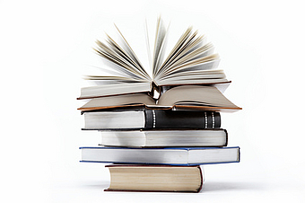 Literatur-Schreibnächte Bücherstapel oben auf ein Buch aufgeschlagen (trotzolga_Fotolia)
