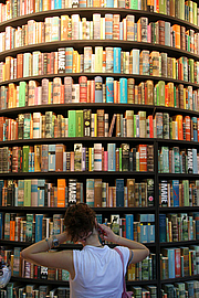 lesen & vorlesen-Newsletter:  Blick auf die Vorderseite des deckenhohen Bücherturms mit bunten Buchrücken 